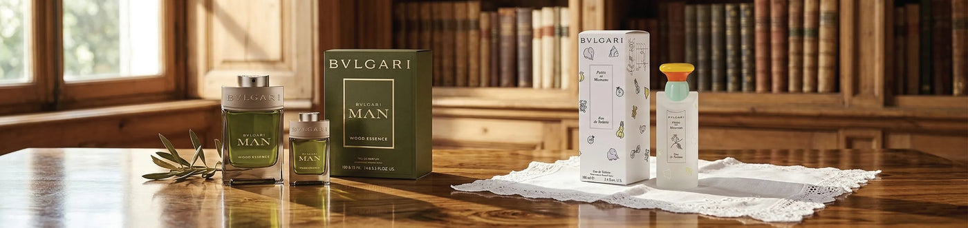 Bvlgari perfume collection in a wooden desk in a library with light shining on the desk from a window. Bvlgari man wood essence, and bvlgari  petits et mamans